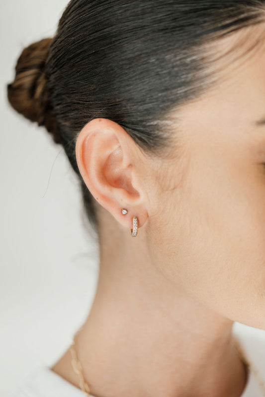 woman wearing diamond studs and huggies