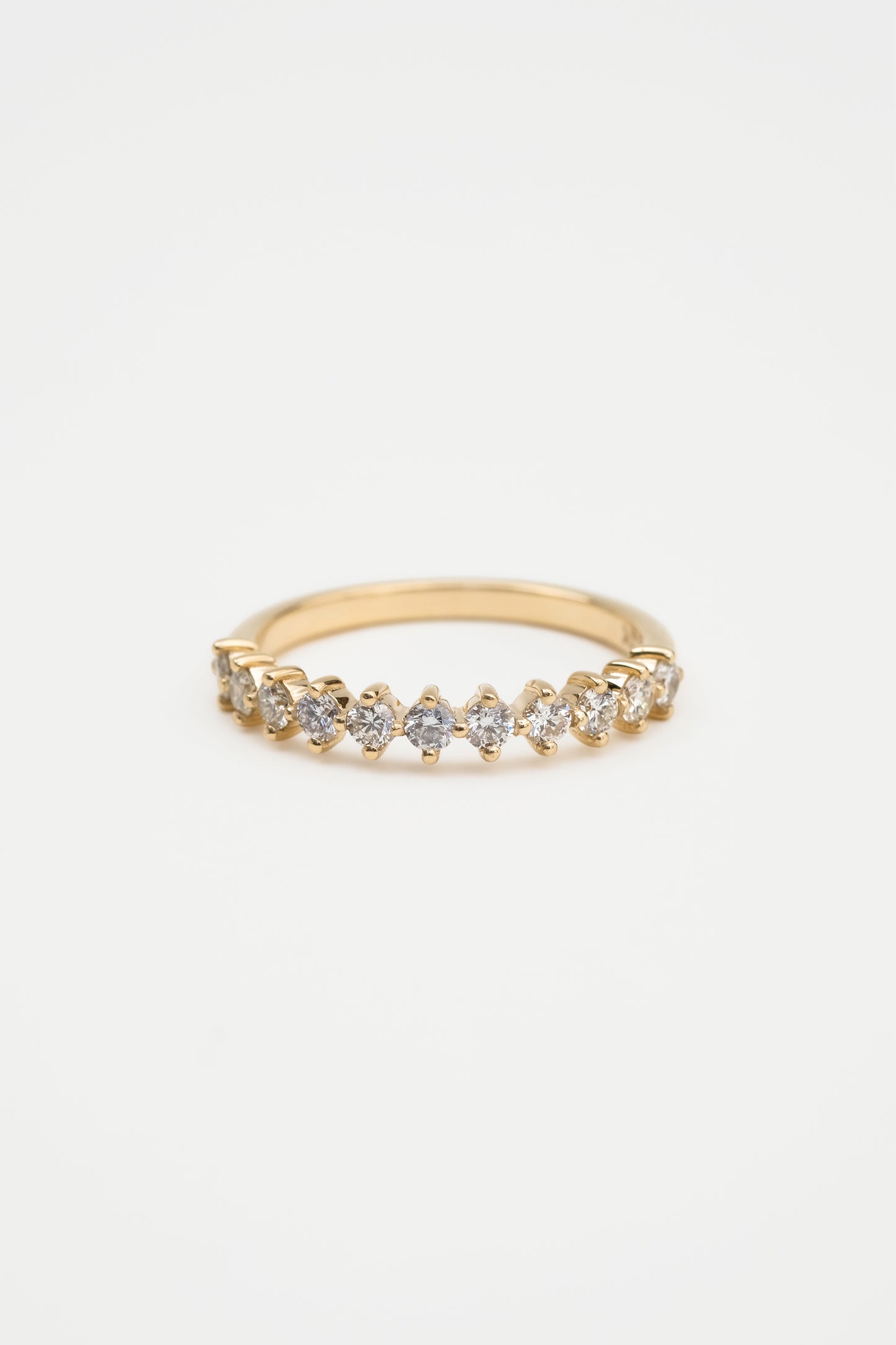 A gold diamond ring with a shared claw setting, featuring a band of round diamonds.