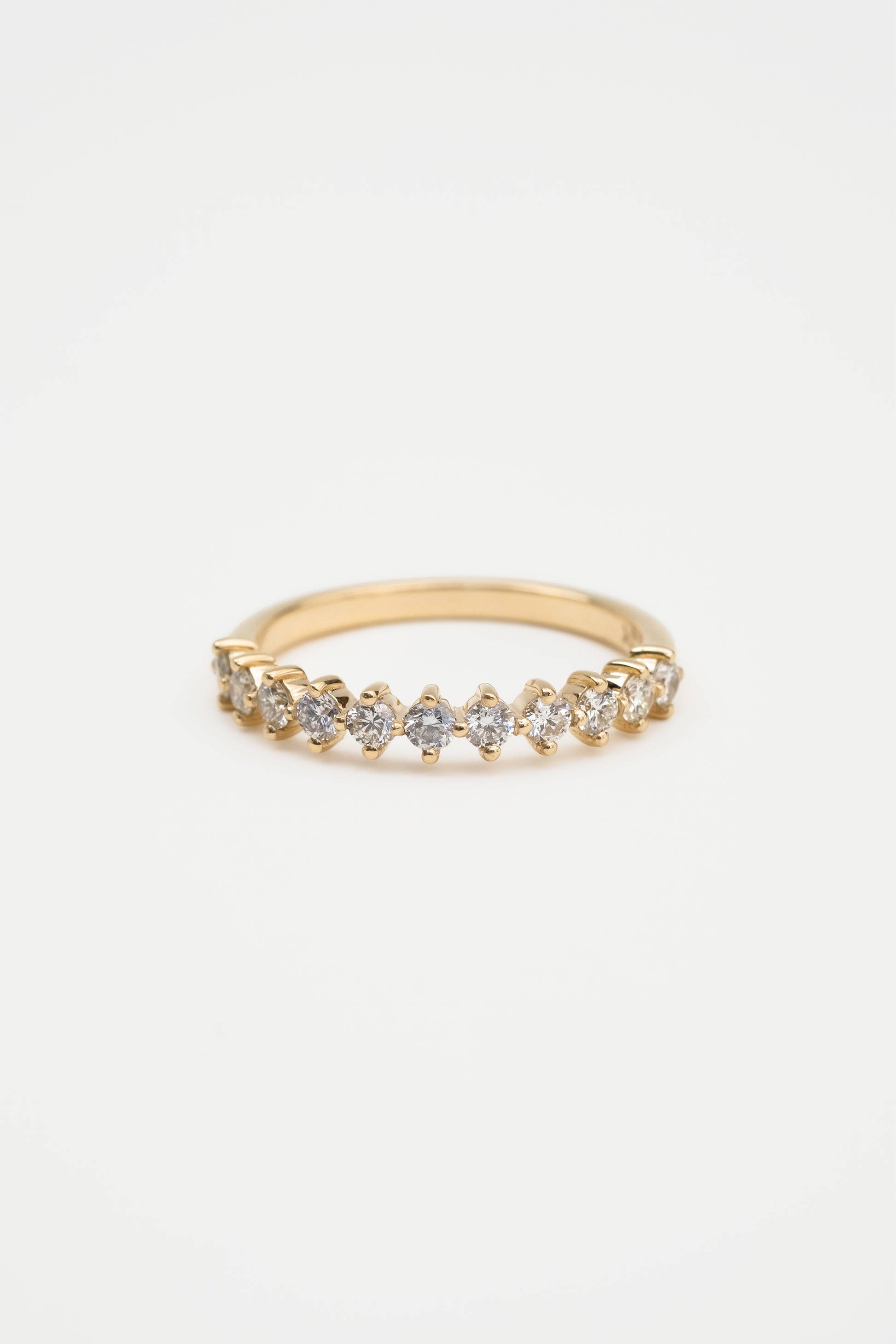 A gold diamond ring with a shared claw setting, featuring a band of round diamonds.