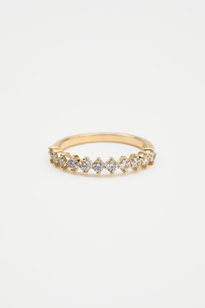 A gold diamond ring with a shared claw setting, featuring a band of round diamonds.