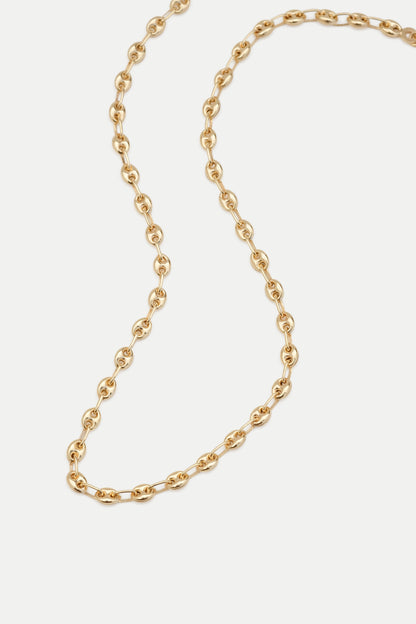 A gold Gucci link chain necklace laid out on a plain surface.