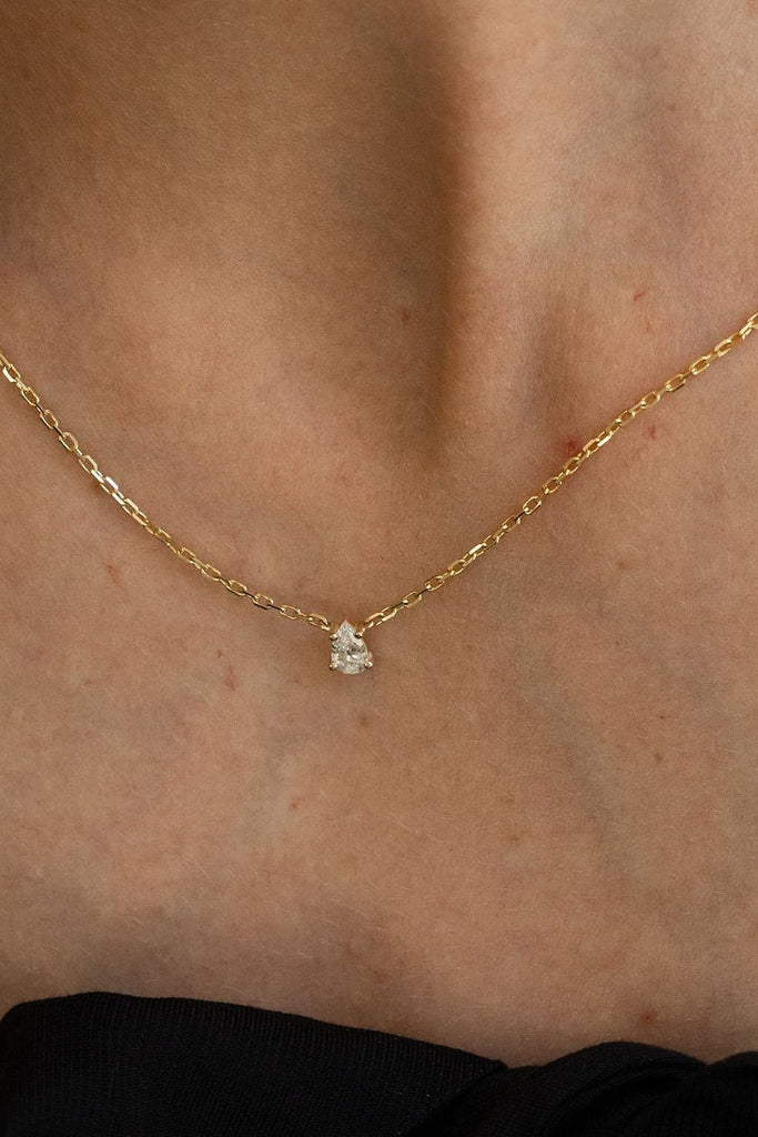 Gold necklace with a small pendant on a person's neck