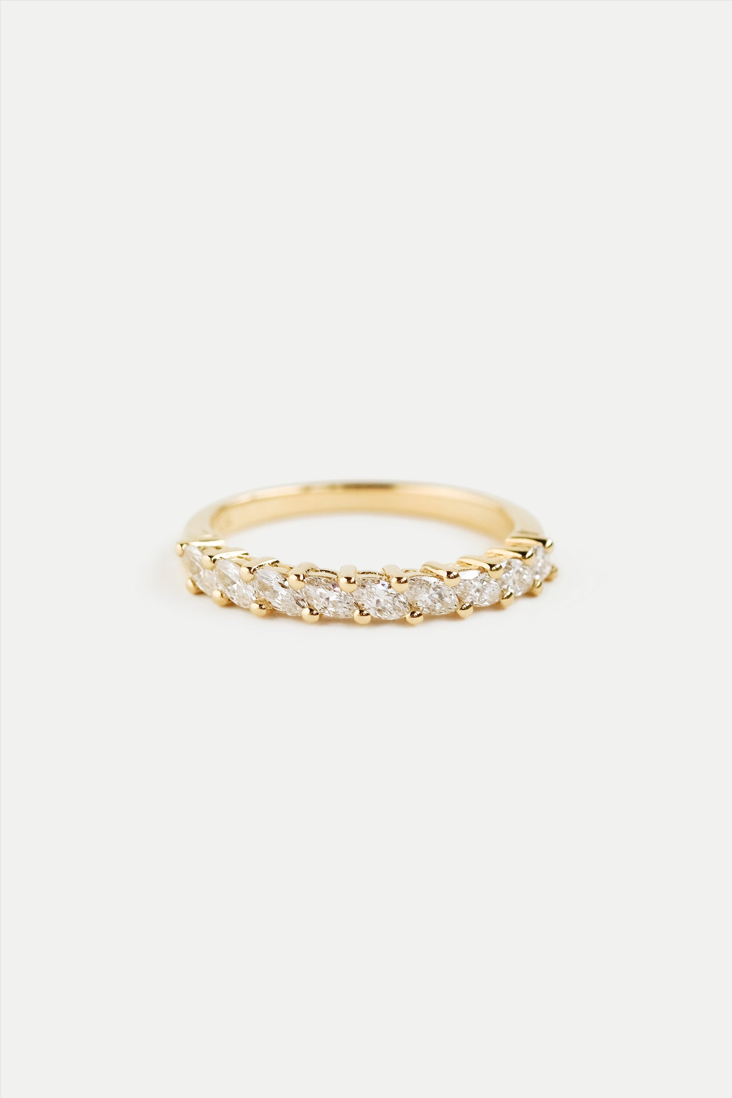 A gold half eternity ring with marquise diamonds set around the band.