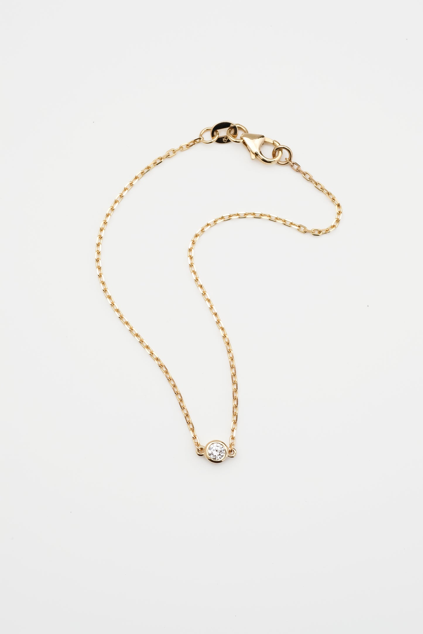 Gold bracelet with a round diamond, displayed on a white background.