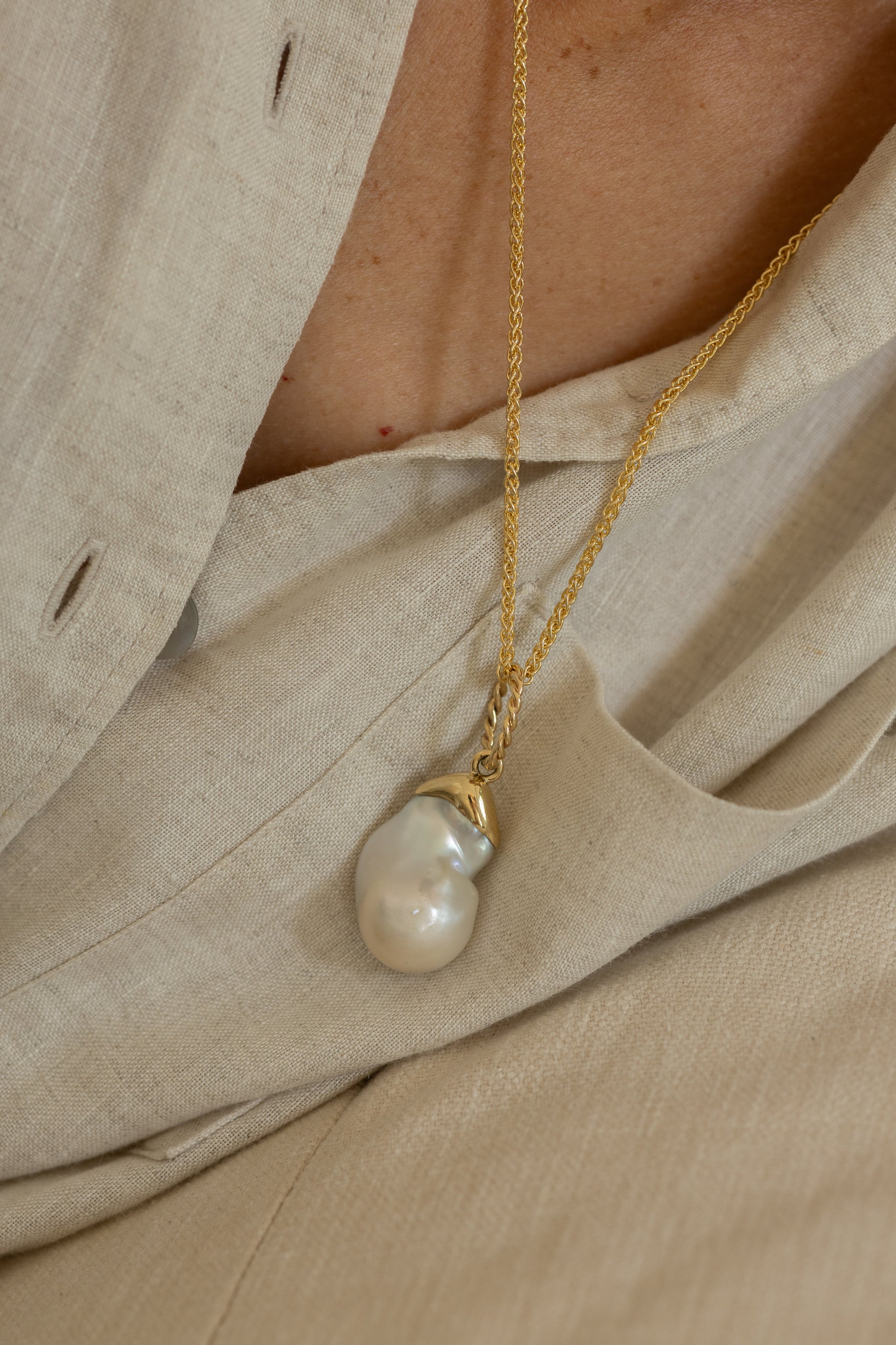 Pearl necklace with gold chain on a beige fabric background