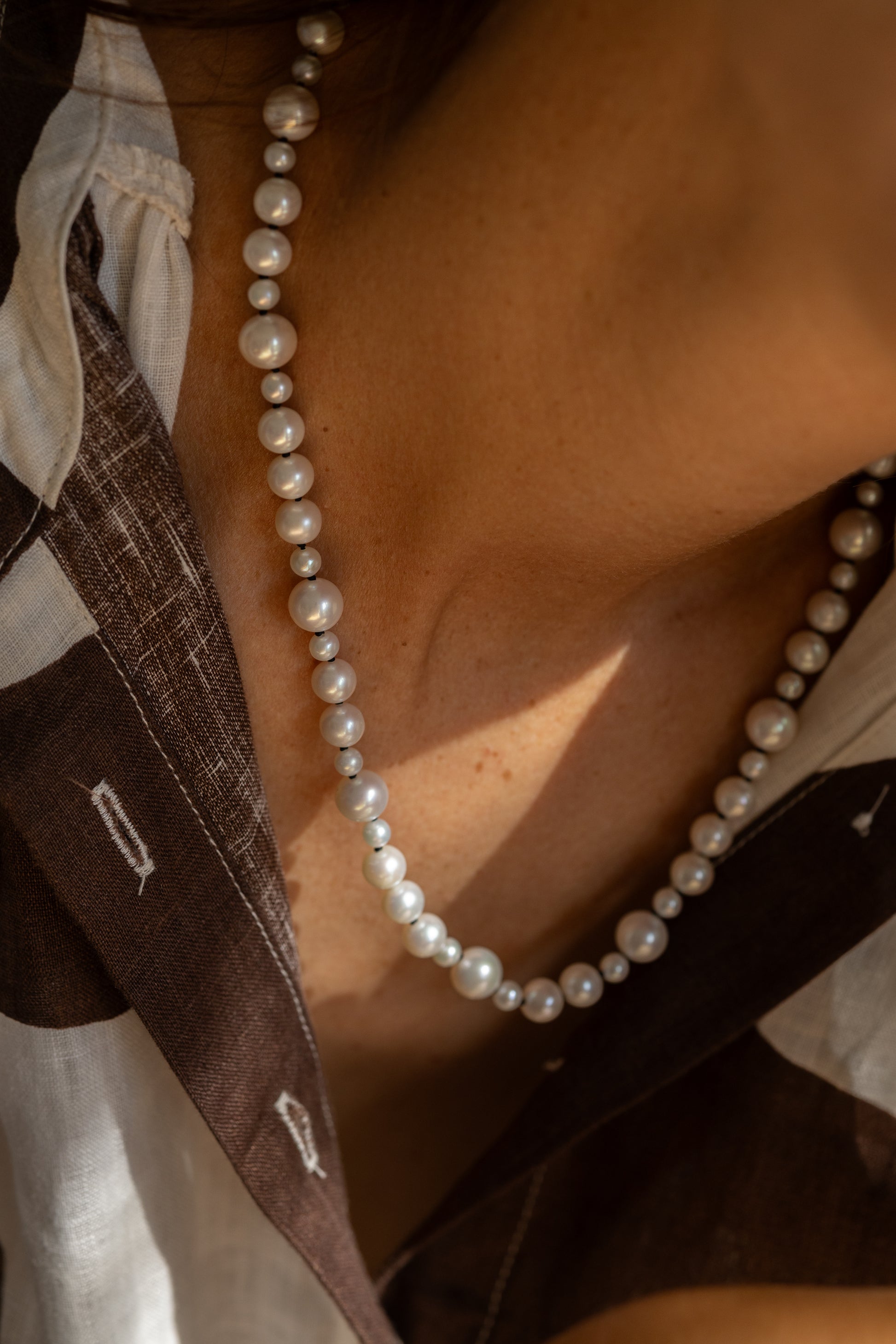 Close-up of a pearl necklace with pattern shirt