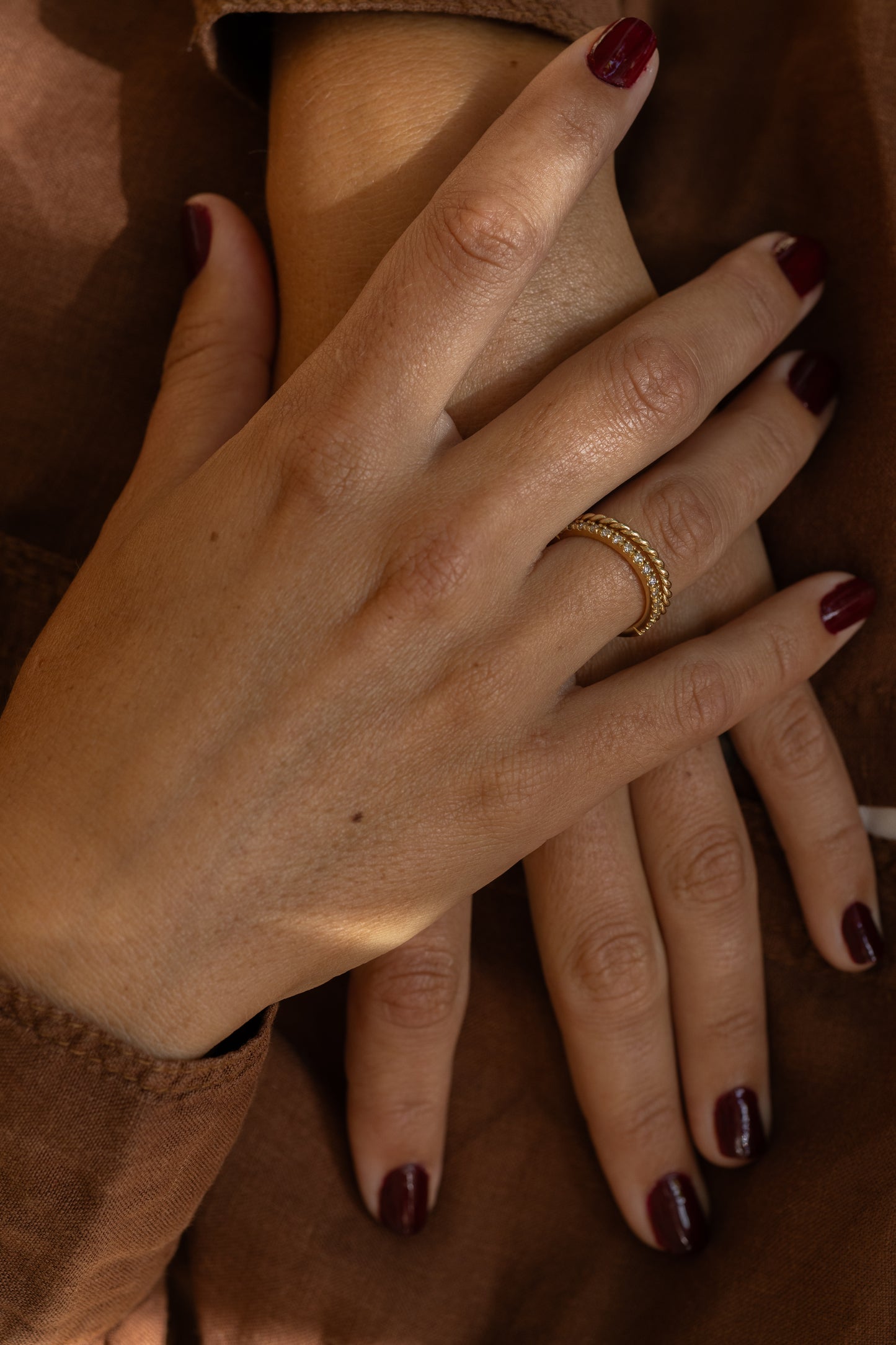 Close-up of a hand with a gold ring on a brown background