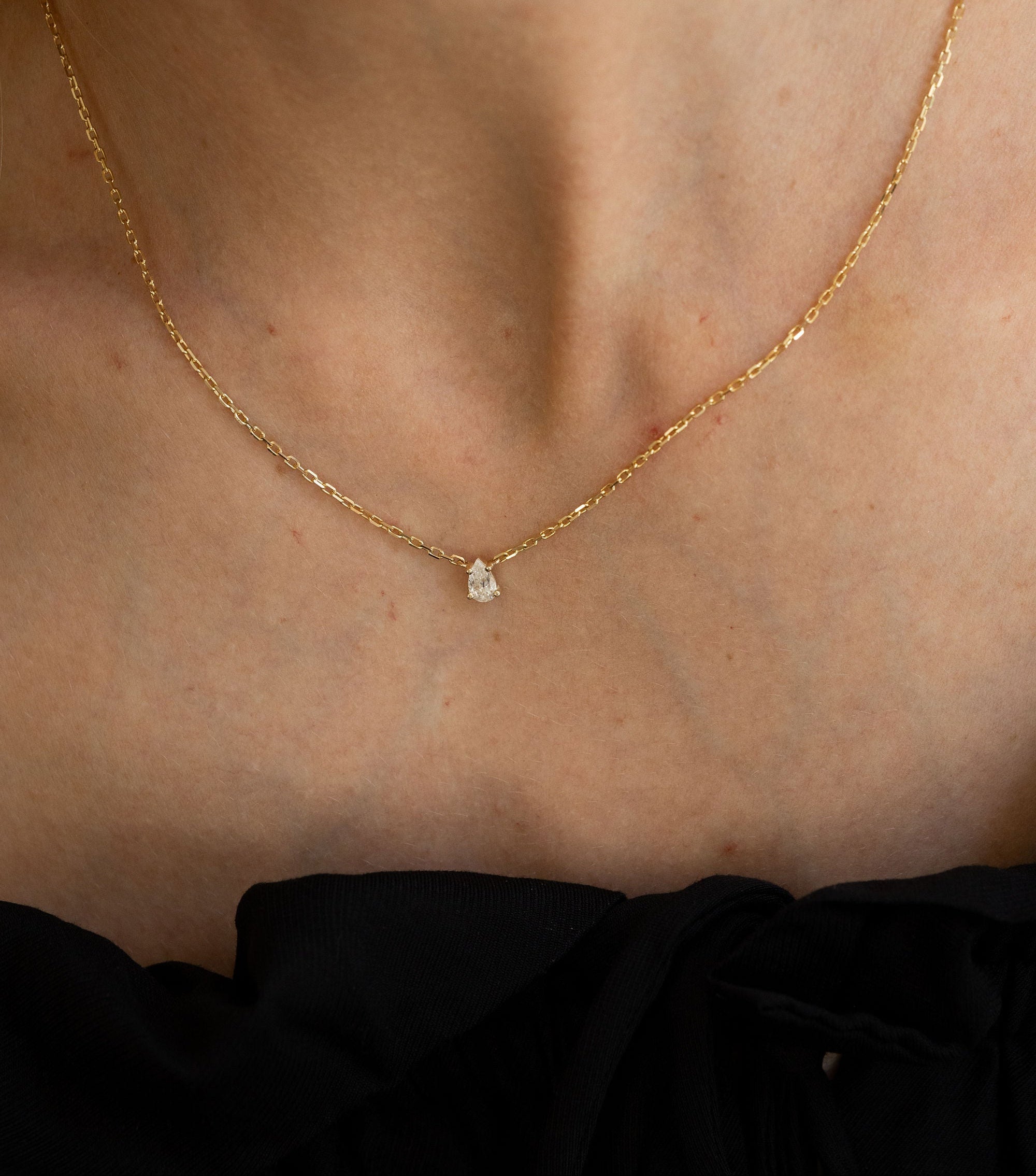 Gold necklace with a small pendant on a person's neck