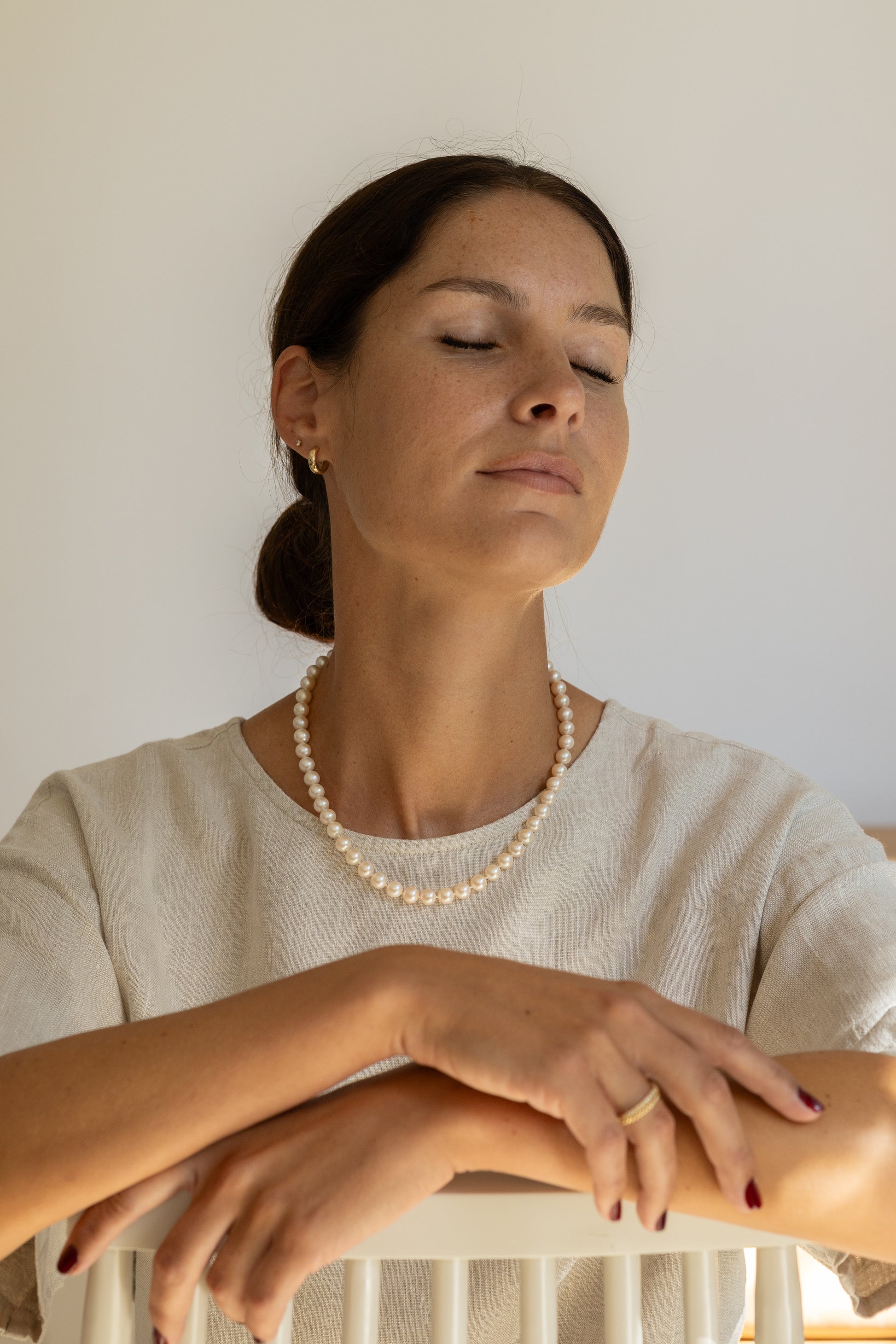 Woman wearing a pearl necklace, with a neutral background