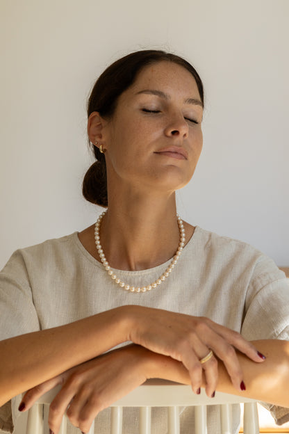 Woman wearing a pearl necklace, with a neutral background